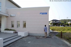 A train station near Sendai. Rob is picture beneath one of the blue signs documenting water height. He is 1.93 m (6'4") and the sign read over 3 m of standing water.